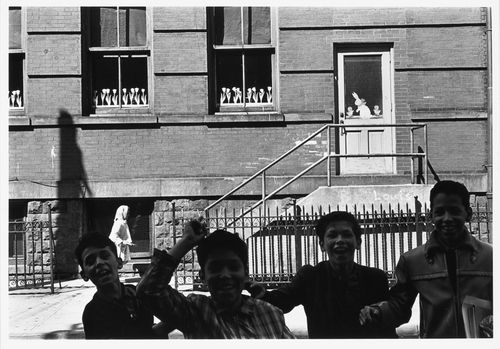 Partial view of a façade of a school [?] with children laughing in the foreground, Hoboken