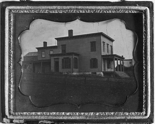 Wood frame house with porch and picket fence, possibly New England, United States