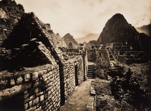 View along a path showing unidentified buildings, the House of Ñusta [princess] and the staircase leading to the Torreón with the Industrial Sector in the background, Machu Picchu, Peru
