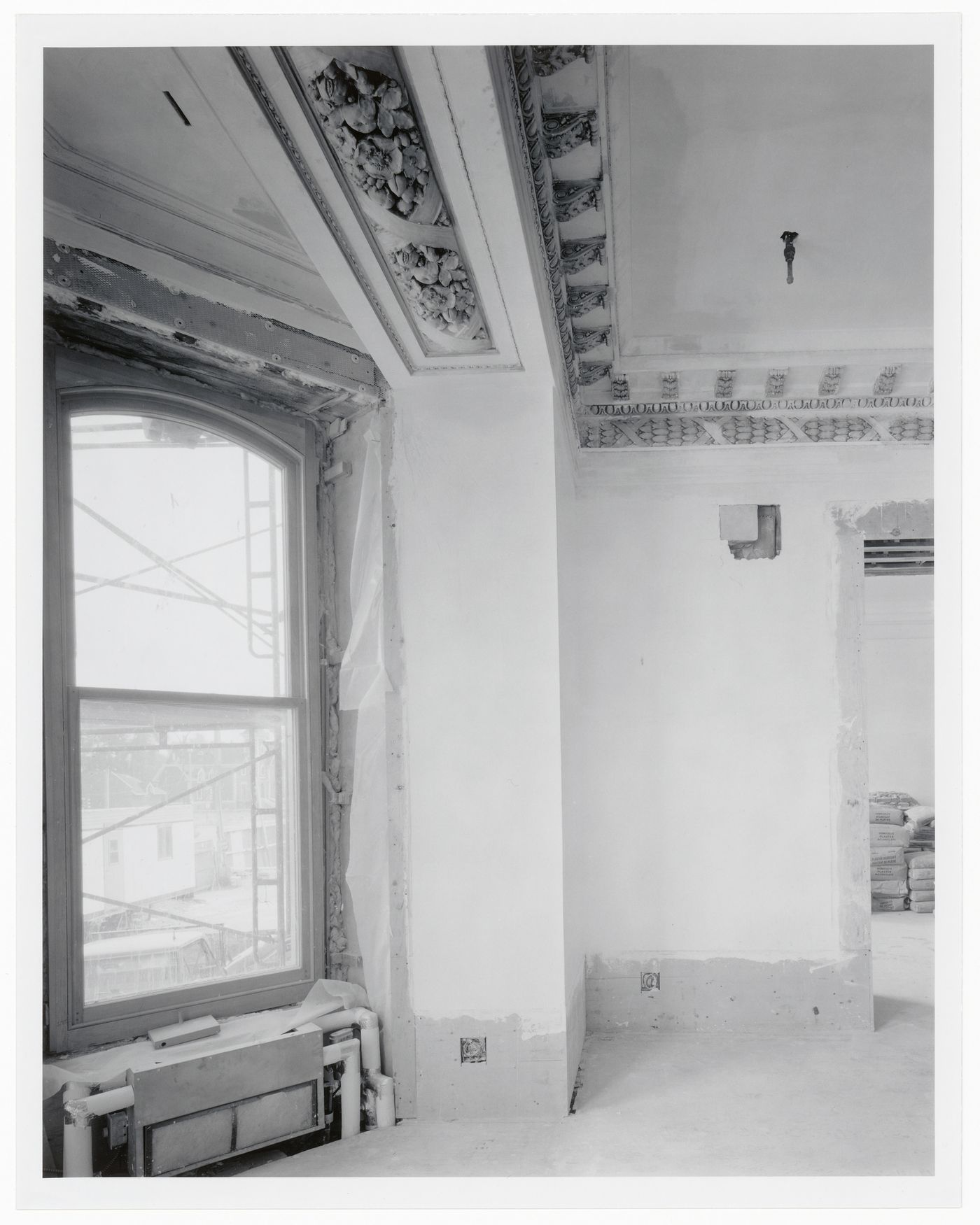 Interior view of a reception room showing a construction workers' trailer through the window, Shaughnessy House under renovation, Montréal, Québec