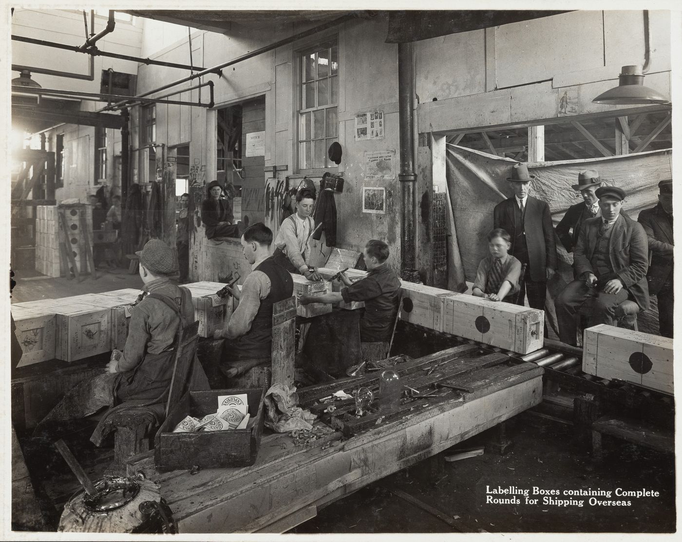 Interior view of workers labelling boxes containing complete rounds for shipping at the Energite Explosives Plant No. 3, the Shell Loading Plant, Renfrew, Ontario, Canada