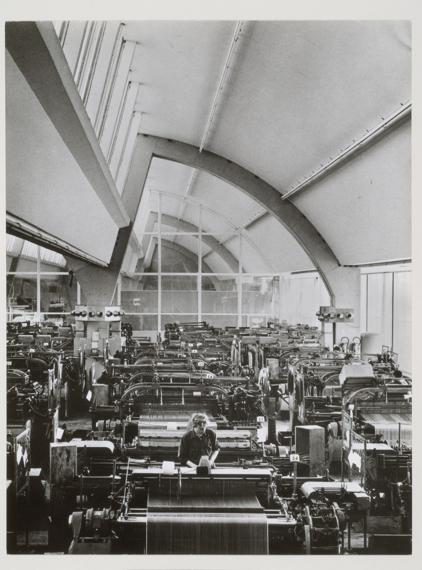 Interior view of De Ploeg Textile Works showing a vaulted room with skylights and power looms, Bergeyk, Netherlands
