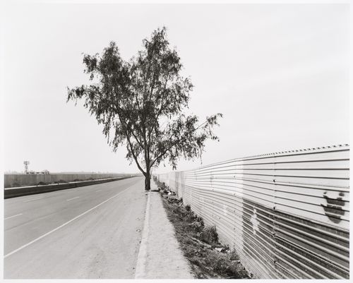 View along a highway leading to the airport in Tijuana, Baja California, Mexico, showing a partial view of the United States-Mexico border fence
