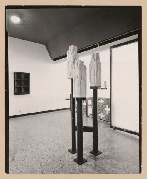Interior view of a gallery showing three sculptures on pedestals with fragments of stone tracery and a bust in the background, Museo Correr, Venice, Italy