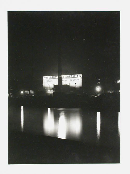 Night view of factory with reflections in river, Berlin, Germany