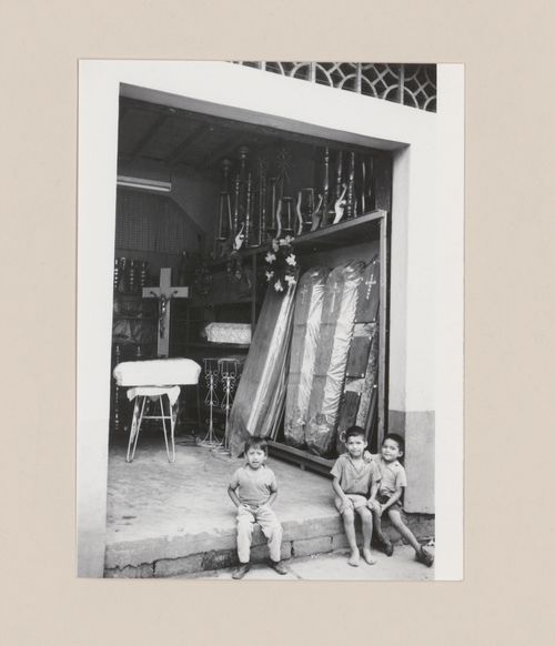 Boys on the doorstep of a storehouse for funerary objects, South America