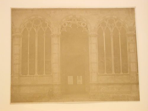 View of a man standing in front of the ornate arcades and an entrance to the loggia of the Campo santo di Pisa, Italy