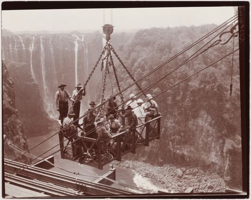 View of a group of men in a crane during construction of the Victoria Falls Bridge on the Zambezi River, crossing the border between Victoria Falls, Zimbabwe and Livingstone, Zambia