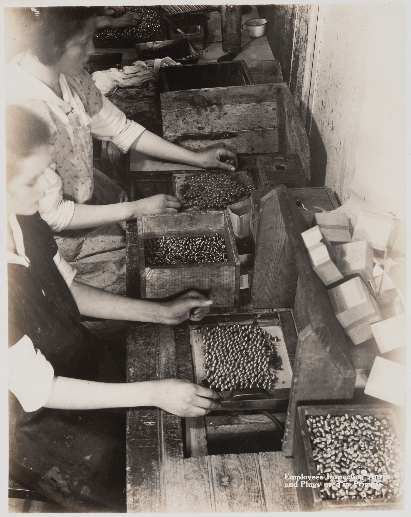 Interior view of workers inspecting anvils and plugs used in primers at the Energite Explosives Plant No. 3, the Shell Loading Plant, Renfrew, Ontario, Canada