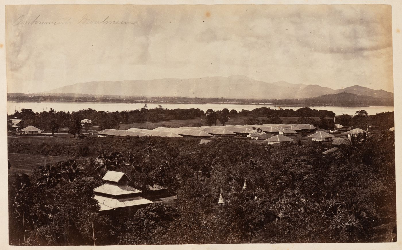 View of buildings with a river, possibly the Salween River, and mountains in the background, Moulmein, Burma (now Myanmar)