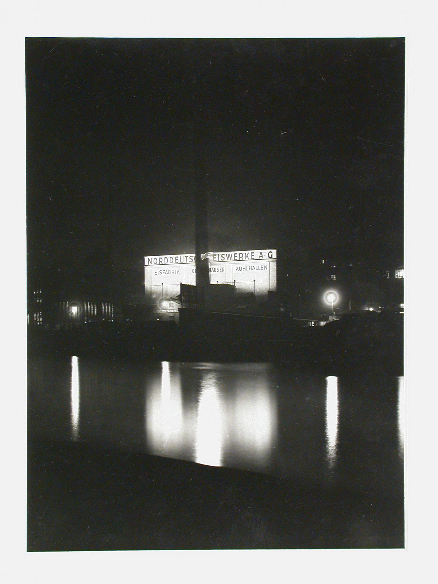 Night view of factory with reflections in river, Berlin, Germany
