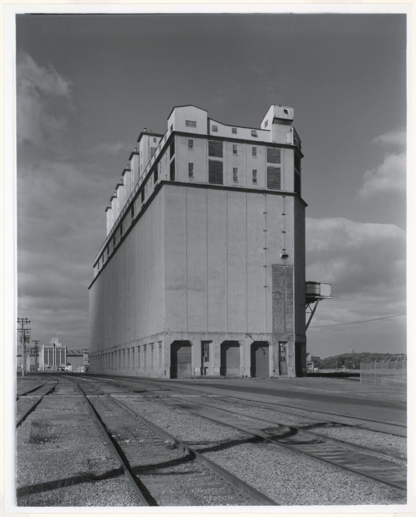 View of the west and north façades of Grain Elevator No. 2 (now demolished) showing railway tracks in the foreground and the Cold Storage Warehouse in the background, Port of Montréal, Québec