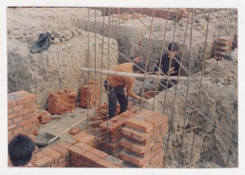 Two workers on the site of housing under construction in China, possibly related to Sichuan housing project