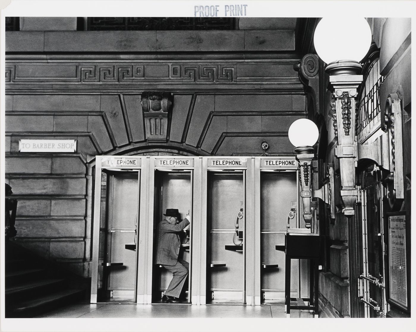 Interior view of the Lackawanna Railroad Terminal showing telephone booths and a man, Hoboken