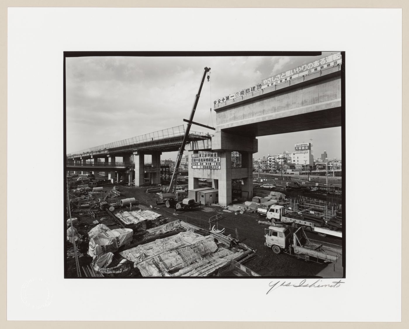 View of an overpass under construction showing construction equipment in the foreground and buildings in the background, Tokyo, Japan