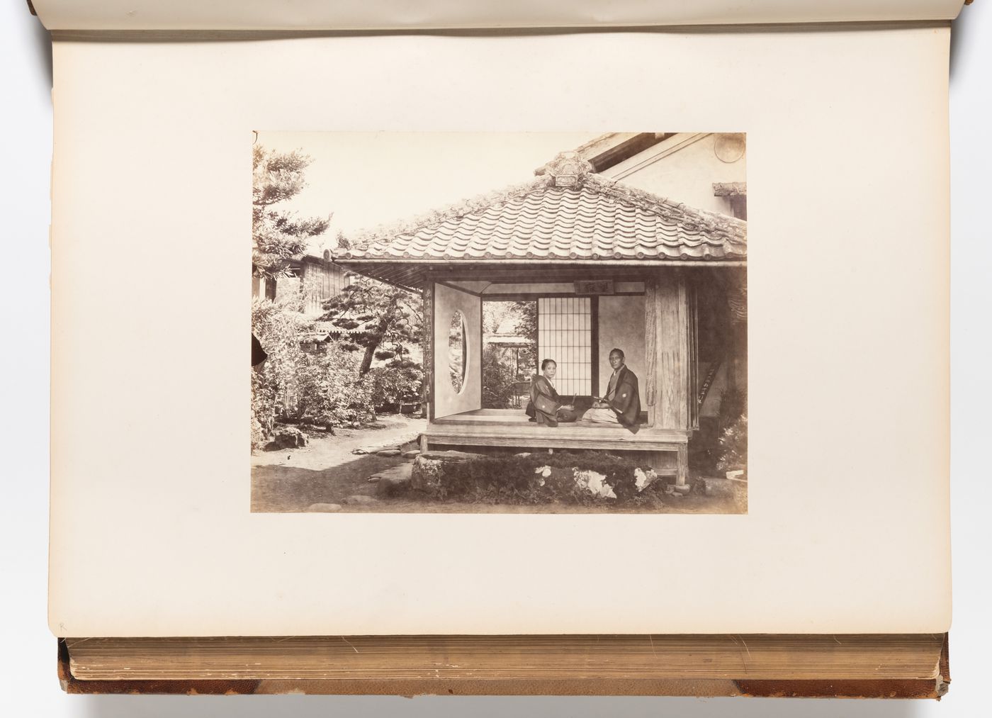 View of a woman and a man sitting in the entrance to a teahouse with a garden in the background, probably Edo (now Tokyo), Japan