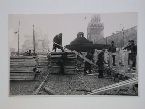 View of workers constructing tribunals adjacent to the second wooden Lenin Mausoleum with Saint Basil Cathedral and Spasskaia Tower in the background, Red Square, Moscow