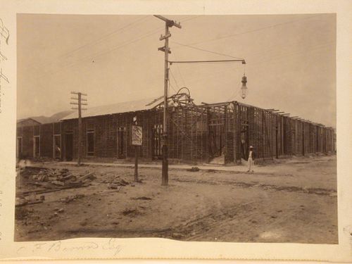 Corner view of housing under construction, man standing on right by corner of buildings