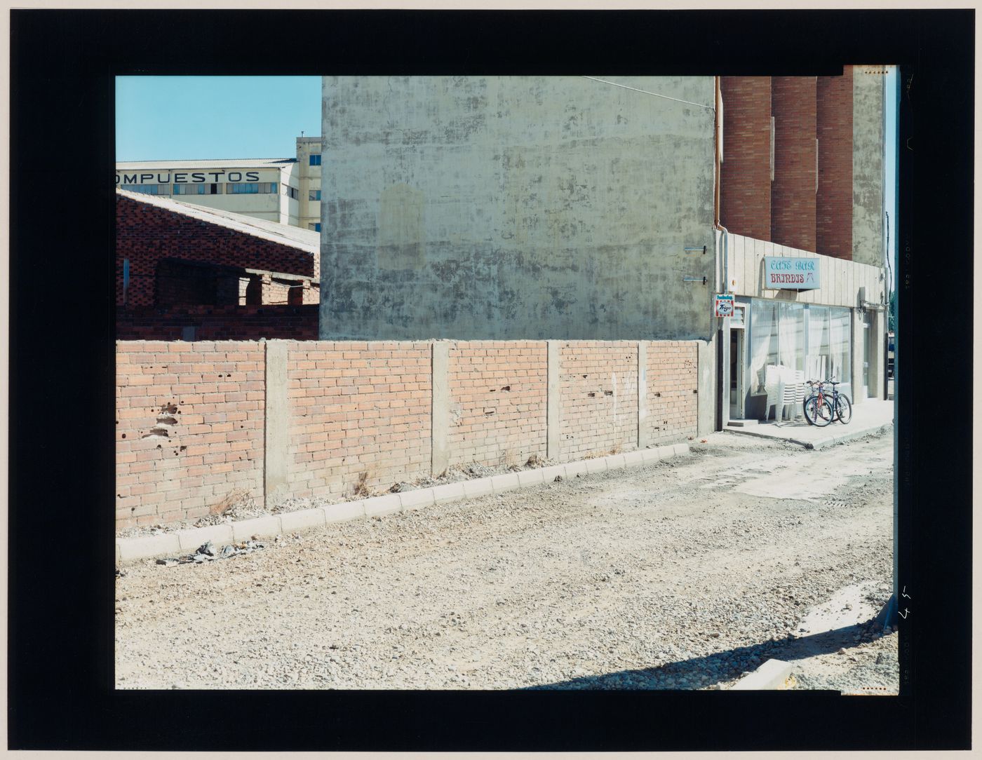 View of a café and other buildings, a brick wall and a dirt road, León, León Province, Spain