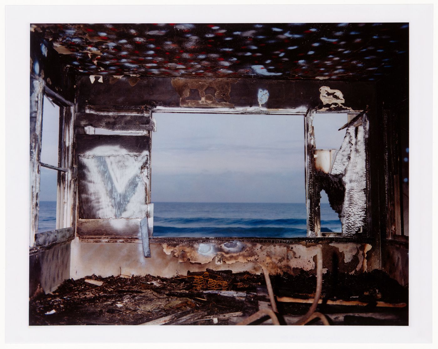 Abandoned (burned-out) beach house, burned trash on floor, charred and graffittied walls and ceiling, California ?