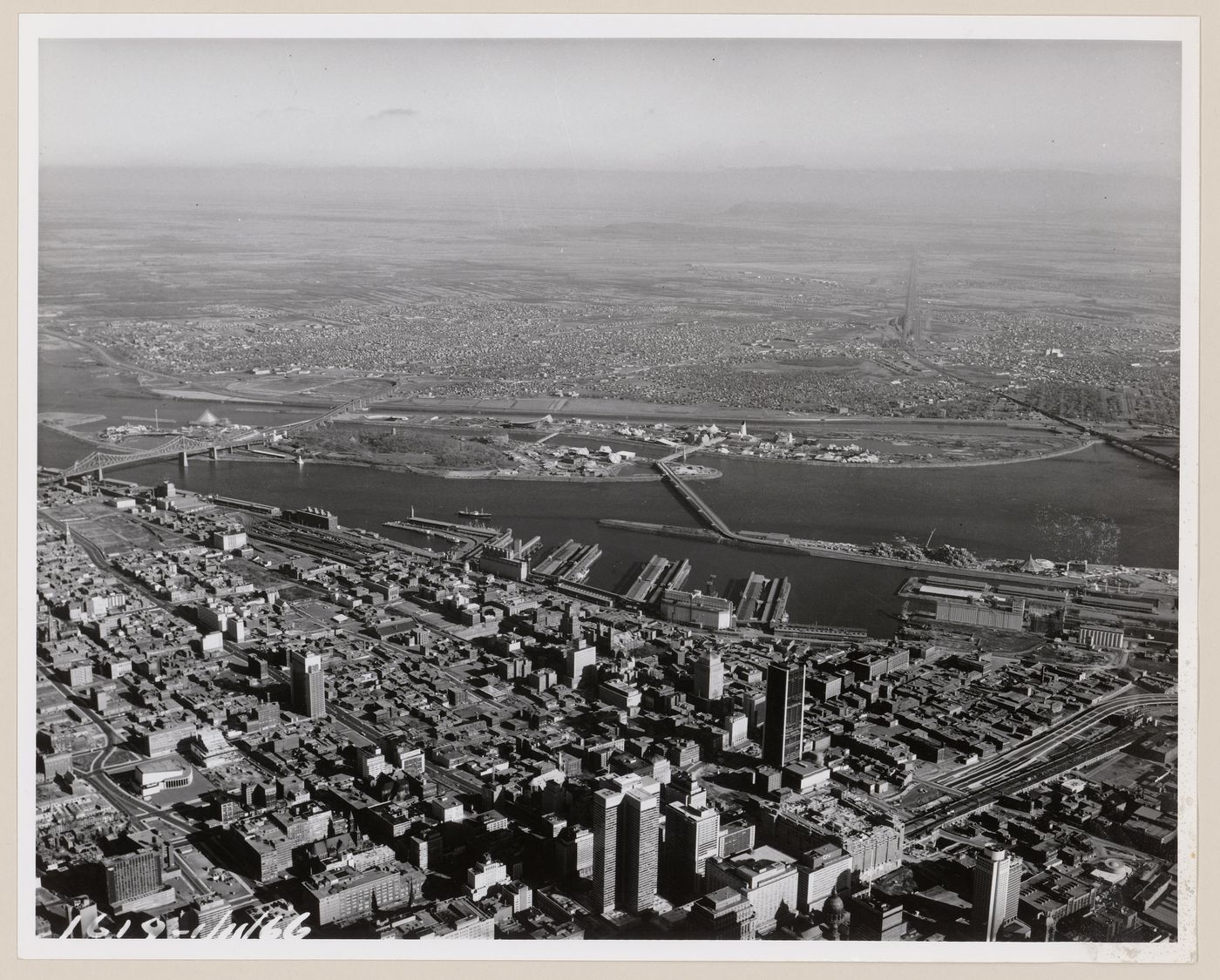 Aerial view of the exhibition sites with Montréal in foreground and the South Shore in background, Expo 67, Montréal, Québec