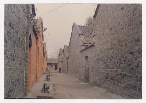 View of a street with houses and two passersby possibly related to Sichuan housing project in China