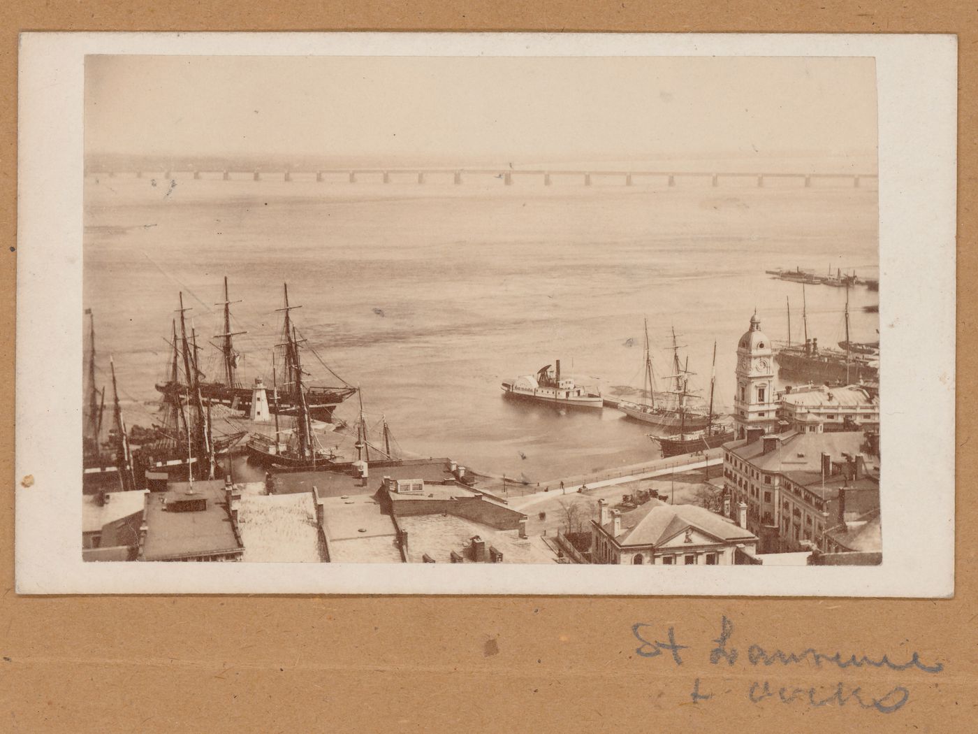 View of the Port of Montréal showing a dockyard, ships, the Maison de la Douane and the Édifice de la compagnie d'assurances Royale (now demolished) with Victoria Bridge in the background, Canada (now Québec, Canada)