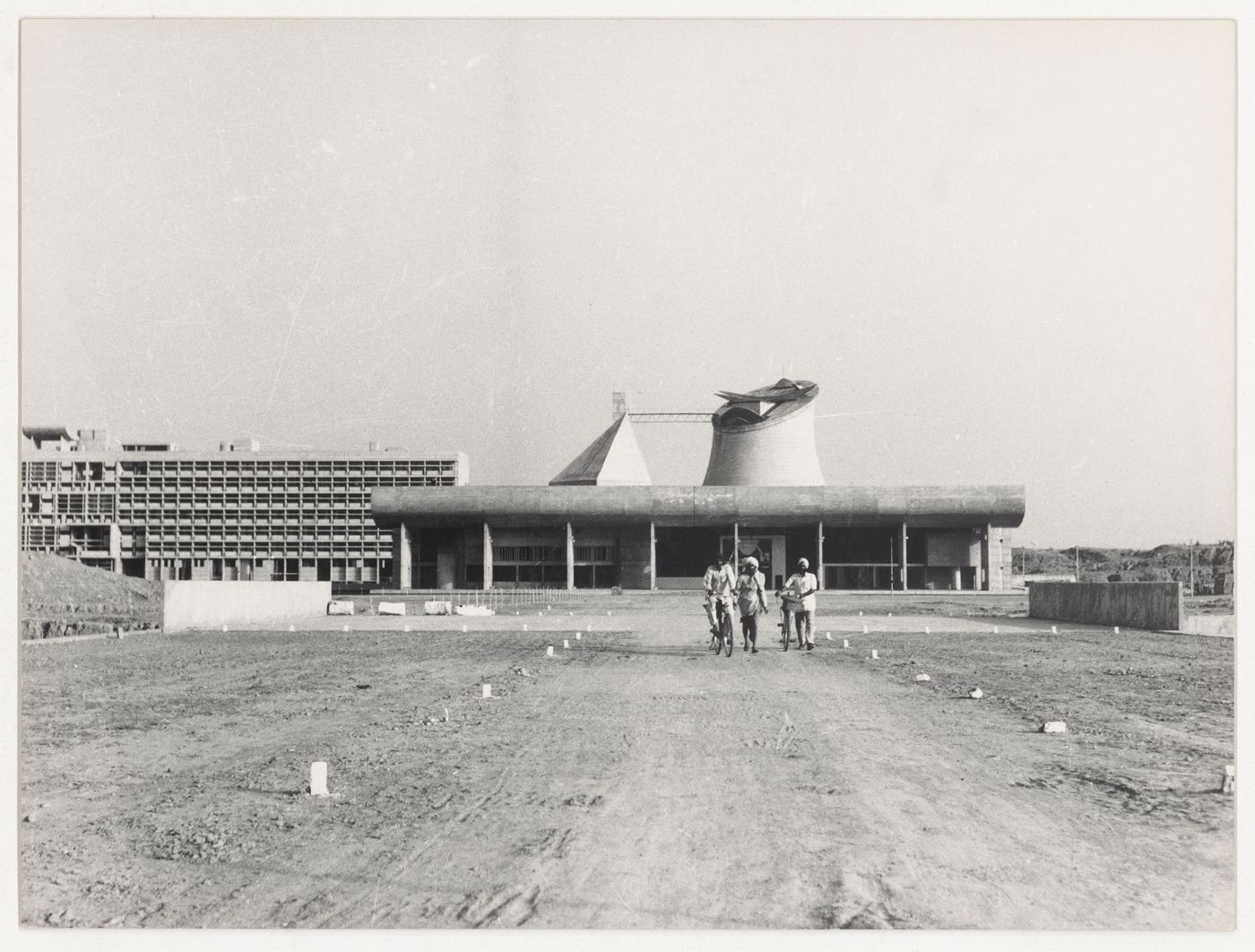 View of men on bicycles and on foot with the Assembly and the Secretariat in background, Capitol Complex, Sector 1, Chandigarh, India