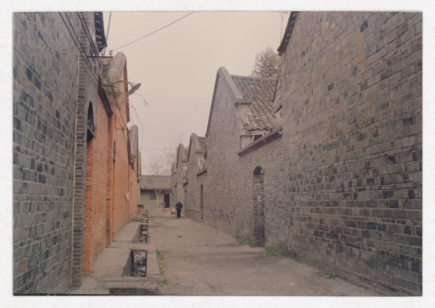 View of a street with houses and two passersby possibly related to Sichuan housing project in China