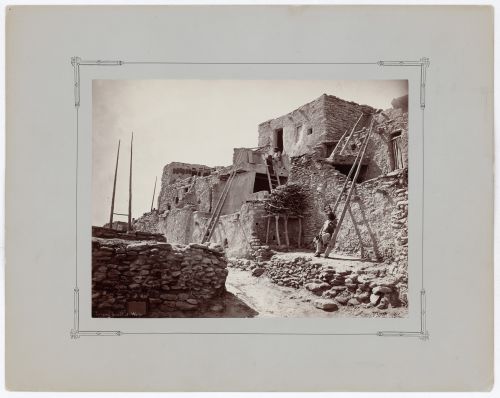 View of Walpi on the First Mesa showing terraced houses and three seated people, Hopi Reservation, Arizona, United States