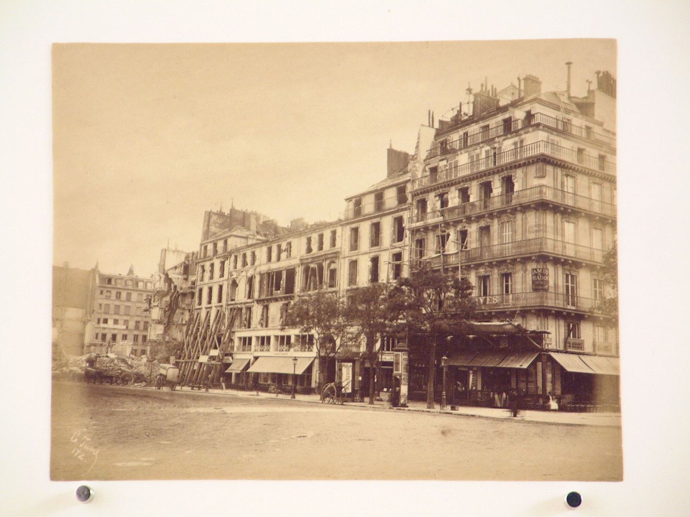 View of a street, possibly the rue Royal, from the Eglise de la Madeleine, showing cafés, apartment houses, and other buildings after the Paris Commune uprising of 1871, Paris, France