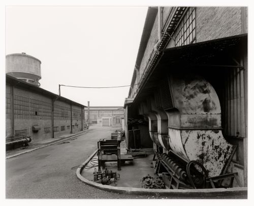 View of a street, buildings, a water tower [?] and machinery, Marghera, Italy