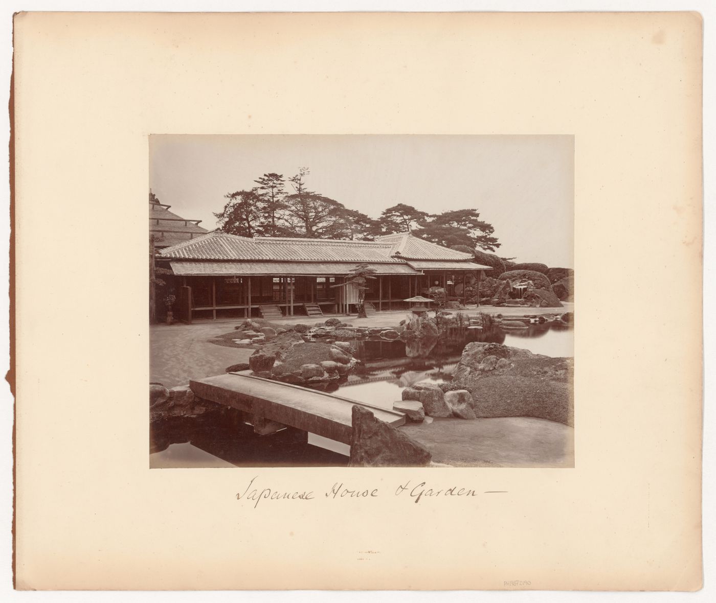 View of a mansion and garden showing a pond and a stone footbridge, Japan