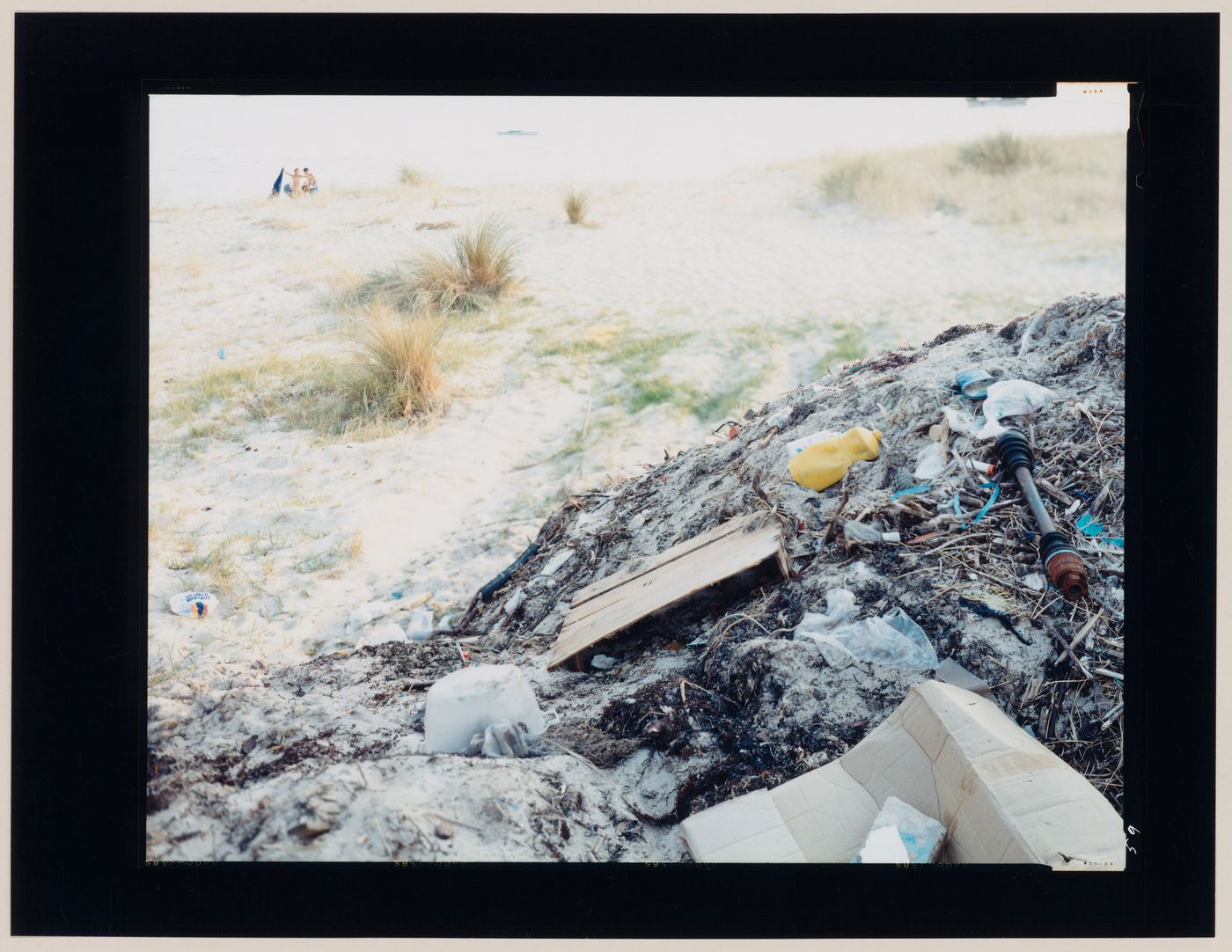 View of a pile of rubbish and a beach showing a family in the background, Cape Finisterre, Spain (from the series "In between cities")