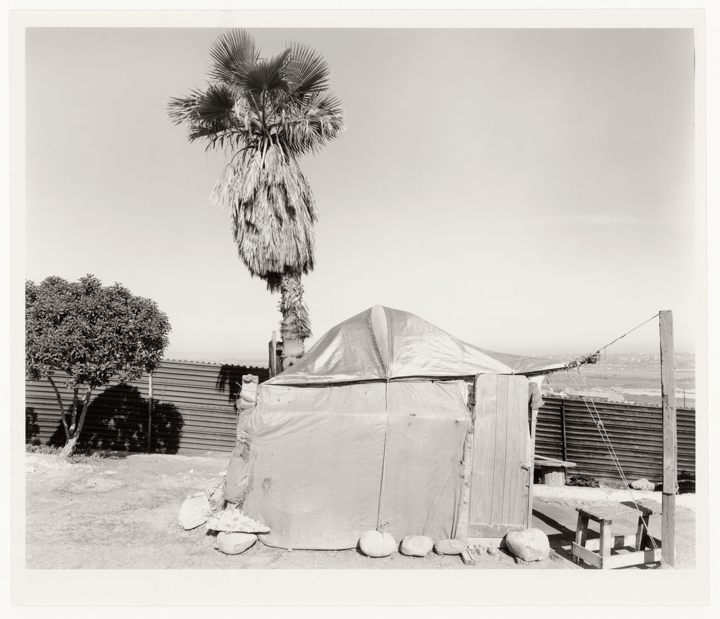 View of  24-hour border crossing supplies tent showing partial view of United States-Mexico border fence, San Diego County, California, United States, and Avenida Internacional, Tijuana, Baja California, Mexico