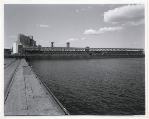 Distant view of Alexandra Pier showing Grain Elevator No. 1 (now demolished) and Shed No. 4 [?] surmounted by the conveyor gallery, Port of Montréal, Québec