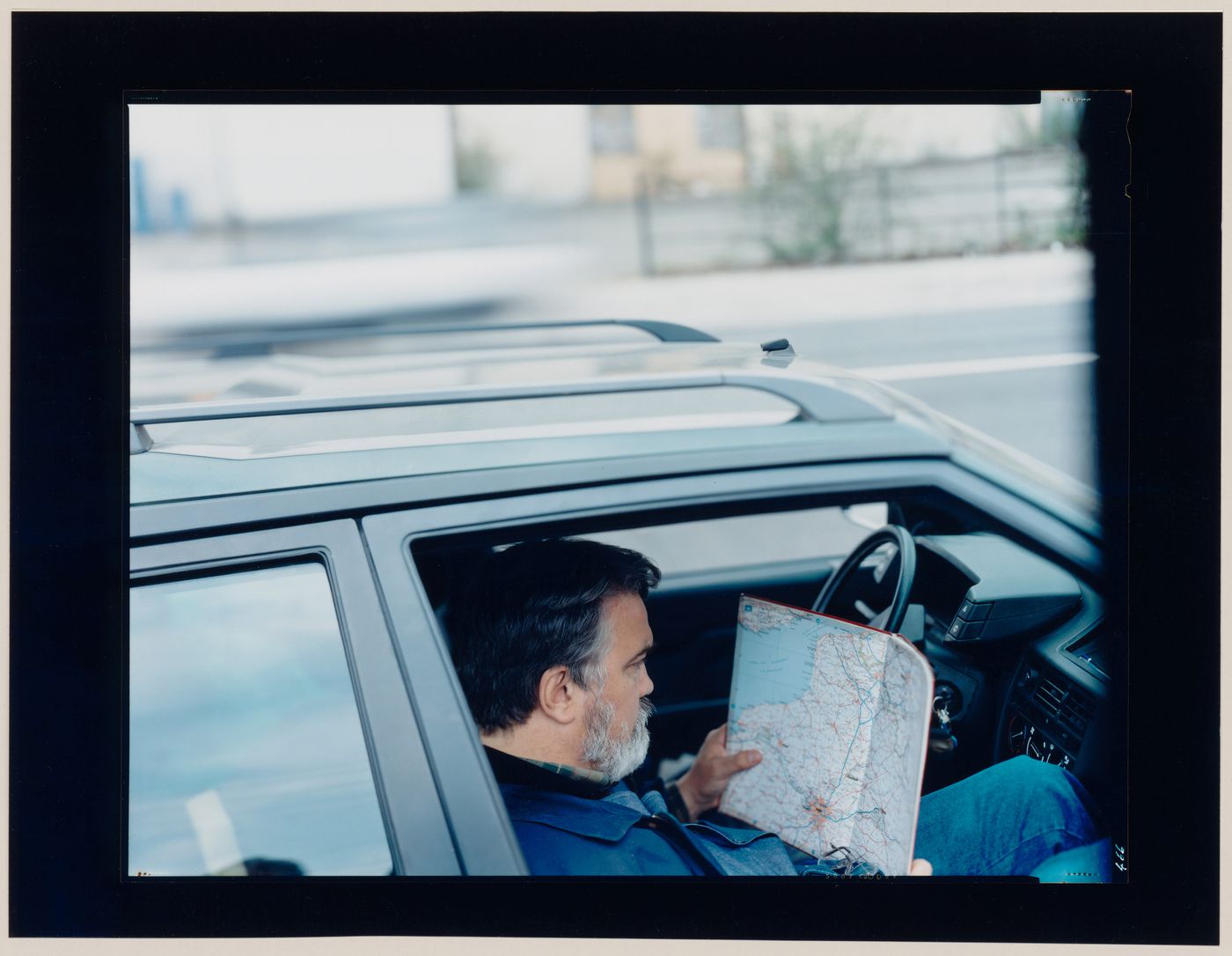 Portrait of a man reading a road map while sitting in a car, Saint-Denis, France (from the series "In between cities")
