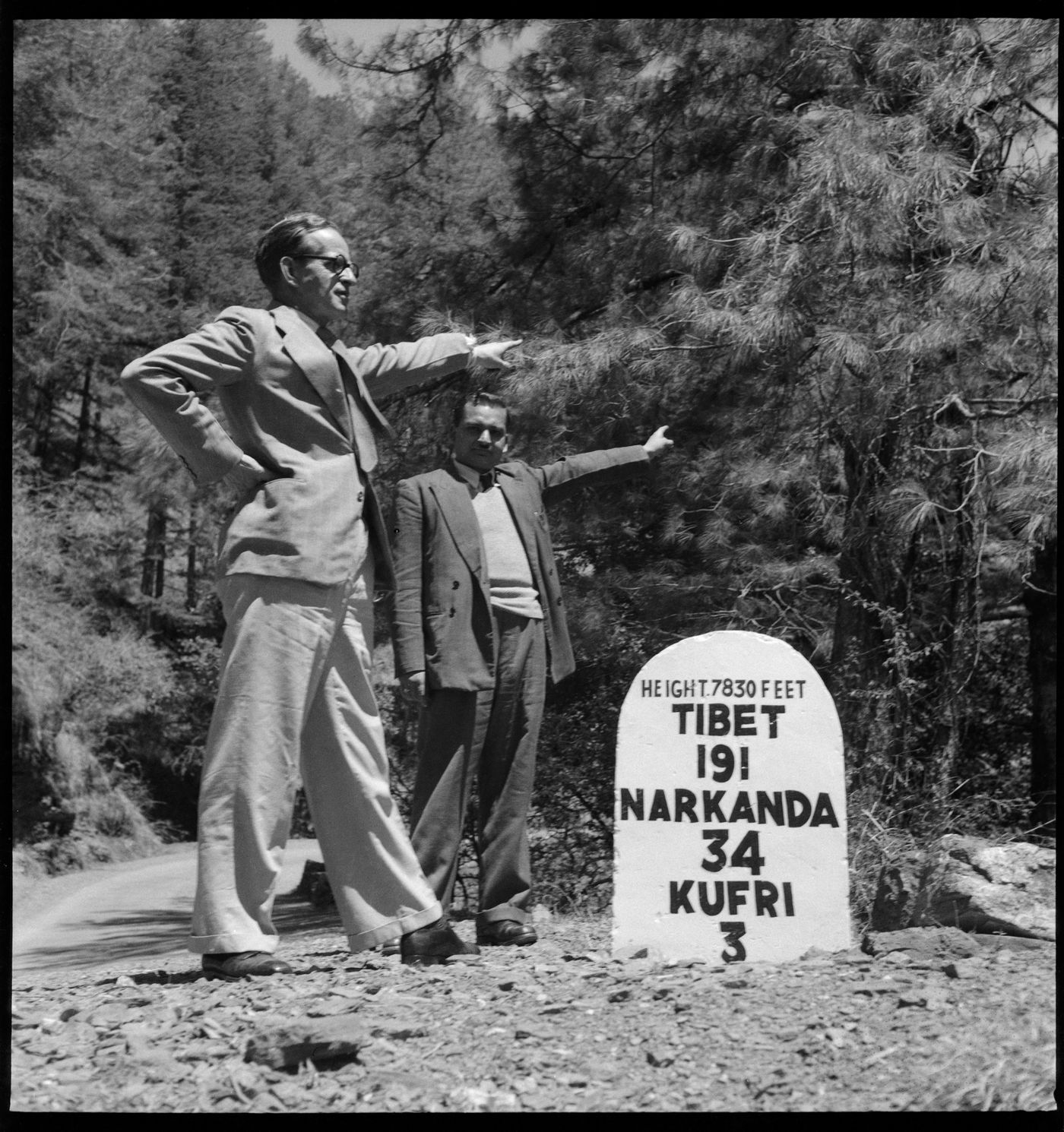 Two men standing near a road sign in India