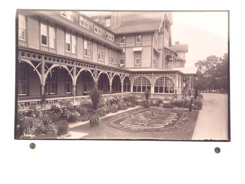 Angled view of front facade, porch and garden of hotel