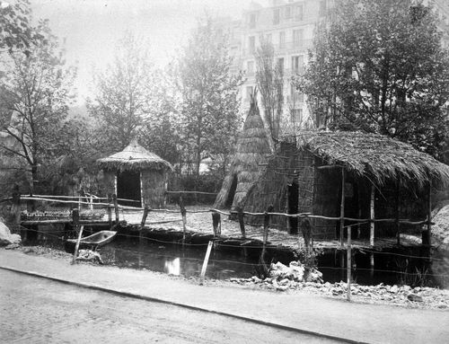 Exposition universelle de 1889 (Paris, France): View of three thatch model houses in a semi-wooded area