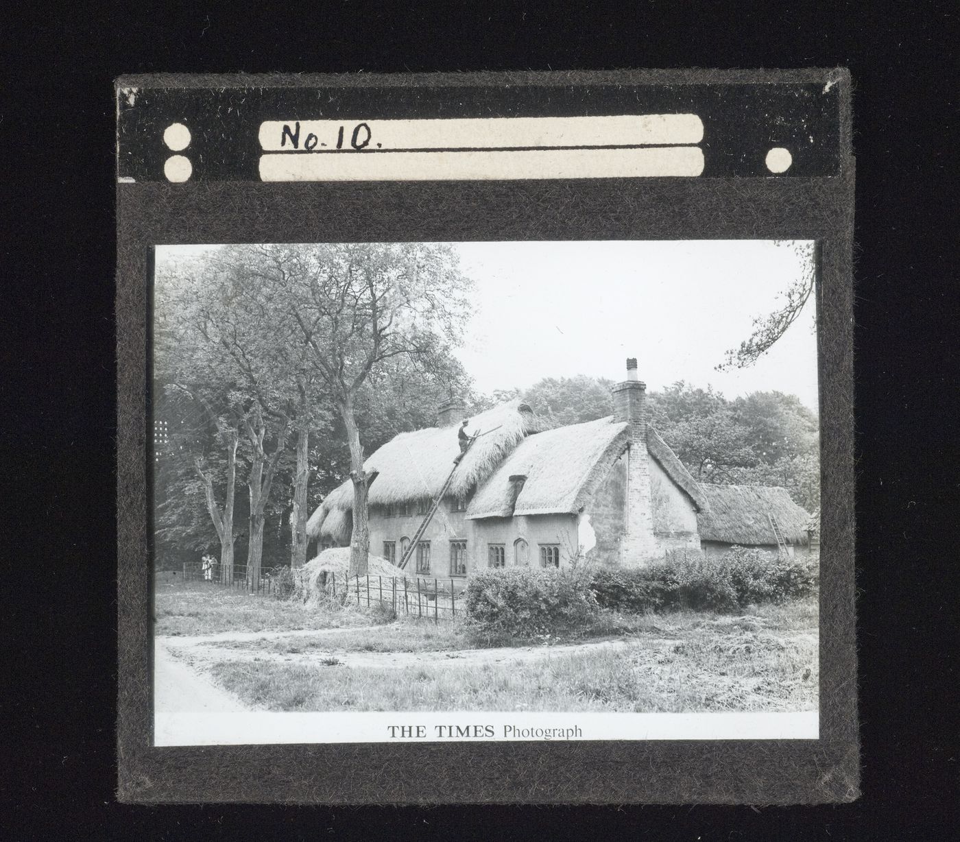 View of croft house with man on ladder working on roof