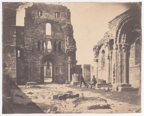 Ruins of Lindisfarne Priory with two figures in middle ground, Lindisfarne, England