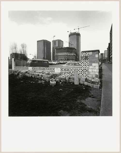 Distant view of Complexe Desjardins under construction with a parking lot in the foreground, rue Sainte-Catherine between rues Jeanne-Mance and Saint-Urbain, Montréal, Québec