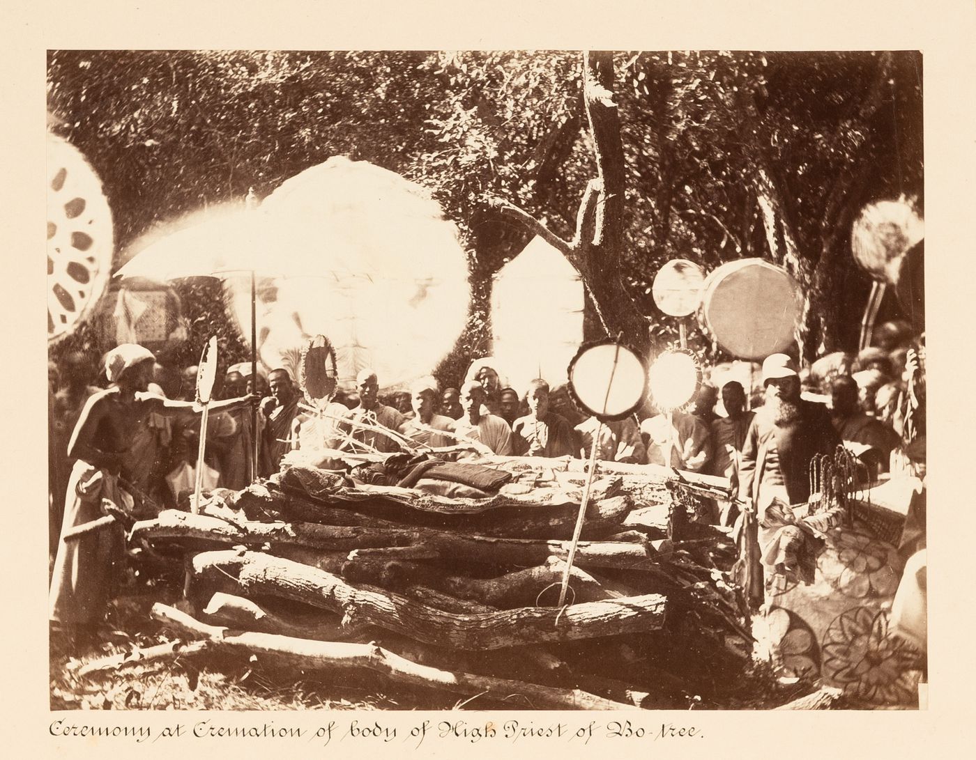 View of a ceremony taking place around the pyre and corpse of the High Priest of the Bodhi Tree (also known as the Bo Tree), Bodhi Tree Enclosure, Anuradhapura, Ceylon (now Sri Lanka)