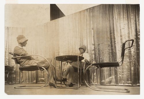 Interior view of two women sitting in chairs designed by Mies van der Rohe beside a table designed by Marcel Breuer, at Lilly Reich's Velvet-Silk Cafe, Berlin, Germany