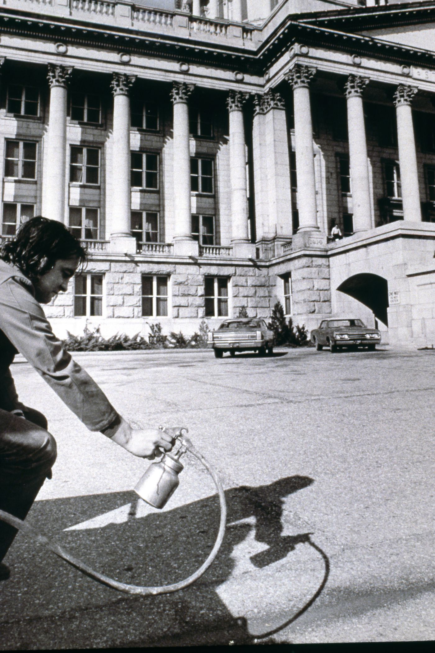 Photograph showing student holding paint sprayer outside Utah State Capitol Building for performance of Red Line