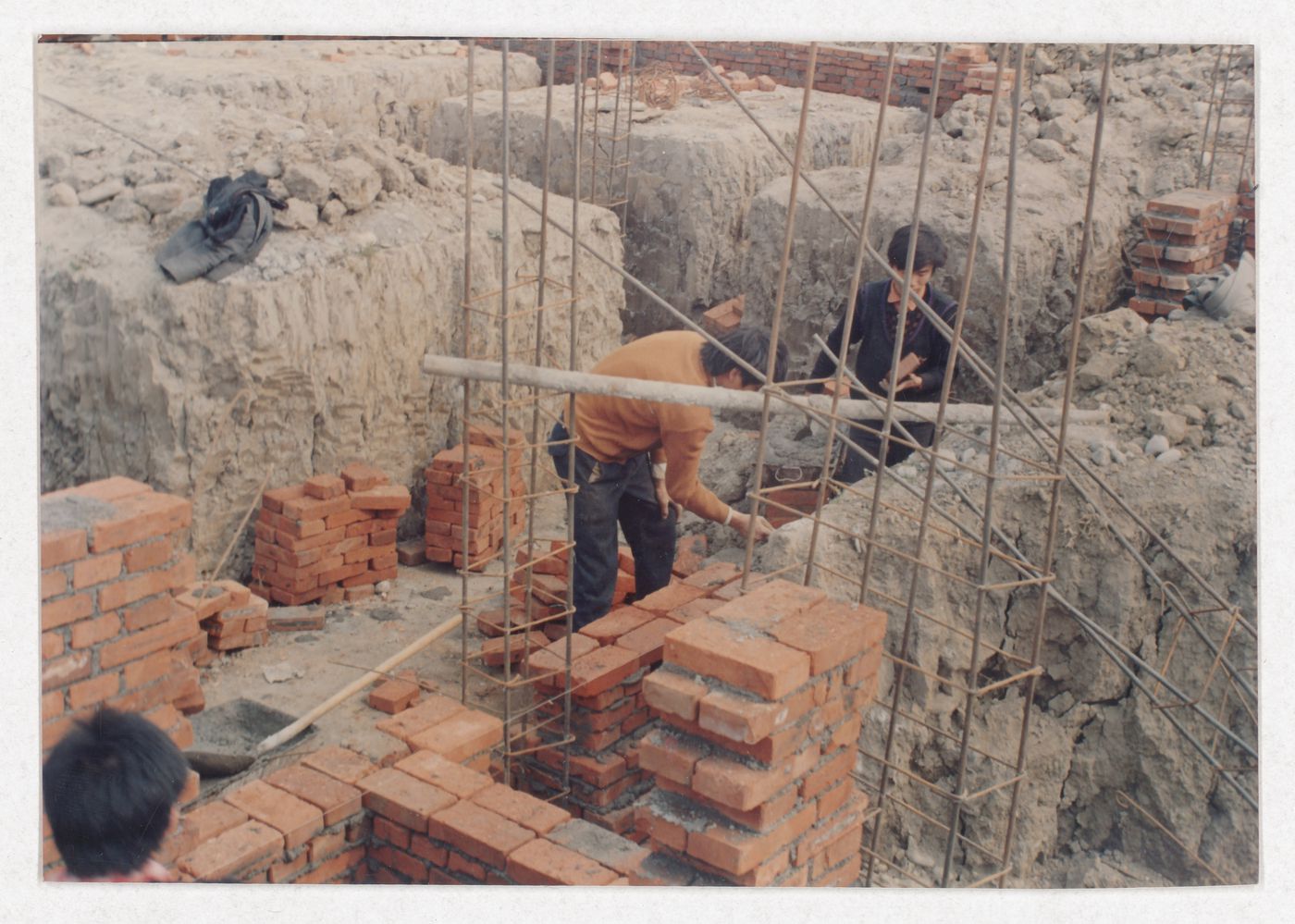Two workers on the site of housing under construction in China, possibly related to Sichuan housing project