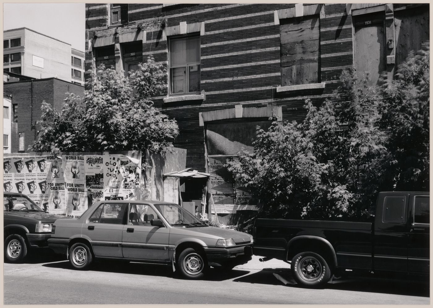 Field Work in Montreal: View of a wooden shack-like structure, a derelict building, parked automobiles, hoardings and posters, Montréal, Québec